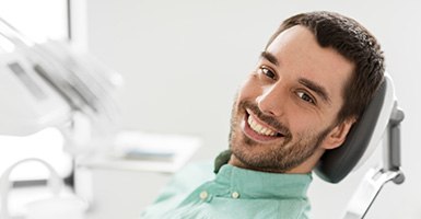 Male dental patient leaning back in chair and smiling