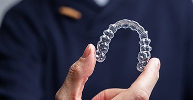 Man holding a SureSmile clear aligner in Odessa, TX