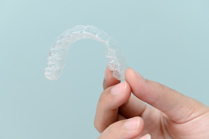 Close-up of hand holding a clear aligner